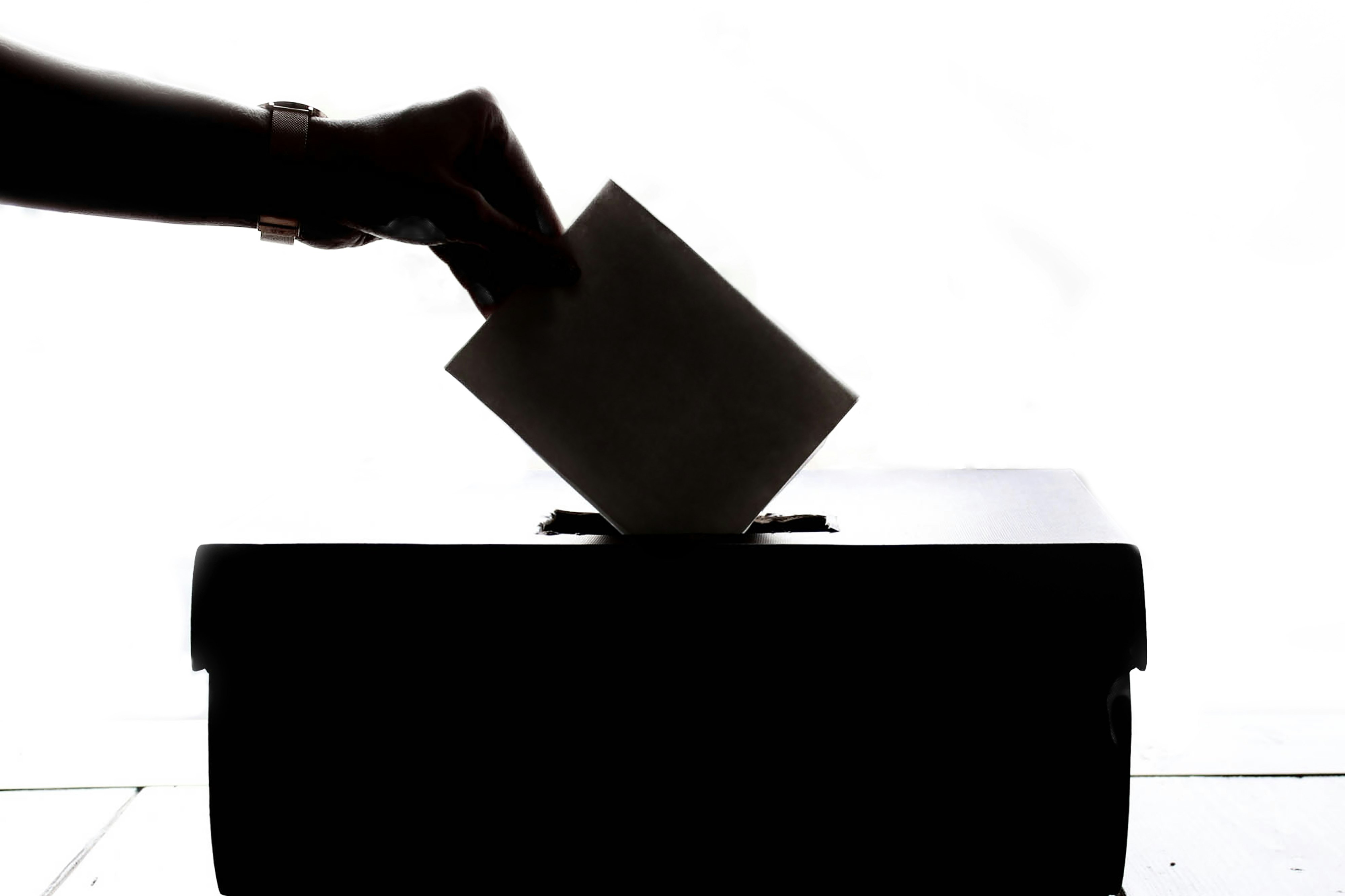 Close-up of hands dropping ballot in box